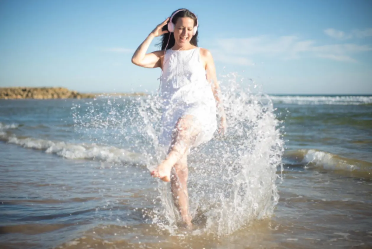 all-inclusive resort getaways-happy woman splashing on the beach